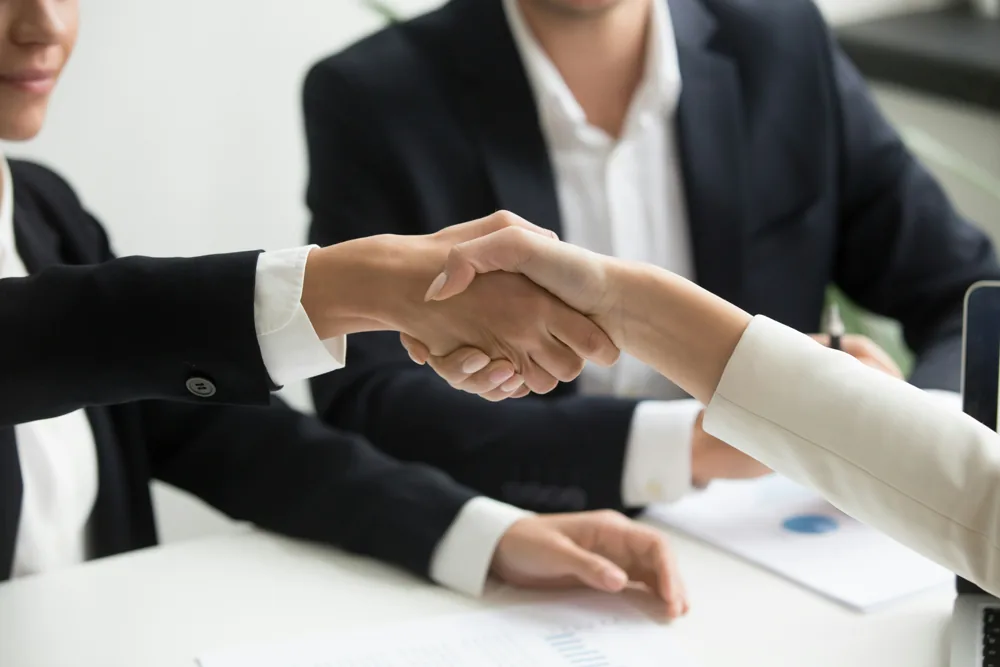 People shaking hands across a table during a meeting